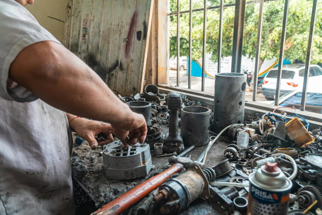 Close-up of a mechanic's hands working with car parts on a workshop table.