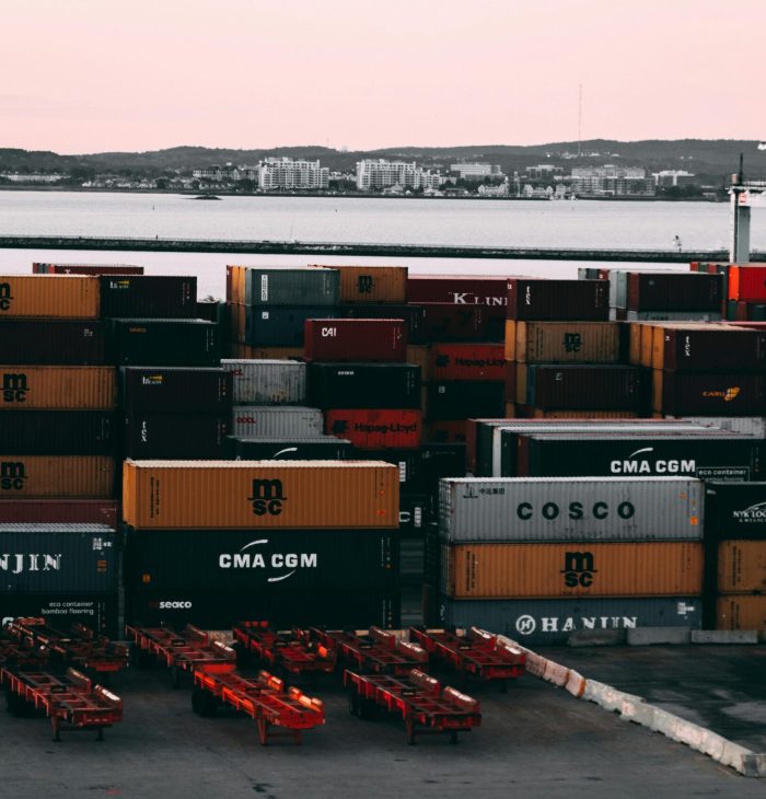 A bustling container yard at a seaport with shipping containers stacked and ready for transport at twilight.