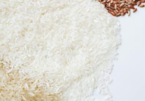 Close-up of assorted uncooked rice demonstrating diversity in grain types on a white background.