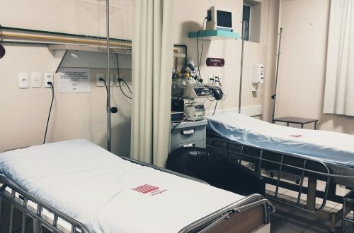 An empty hospital room equipped with two beds, monitoring equipment, and ambient lighting.