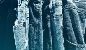 A collection of blue denim jeans hanging closely on a rack in a retail store.