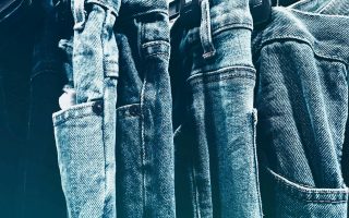 A collection of blue denim jeans hanging closely on a rack in a retail store.