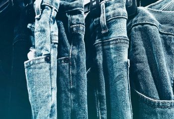 A collection of blue denim jeans hanging closely on a rack in a retail store.